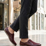 Lifestyle shot of bugatti Canario slip-on shoes in dark red premium leather with mesh detail.
