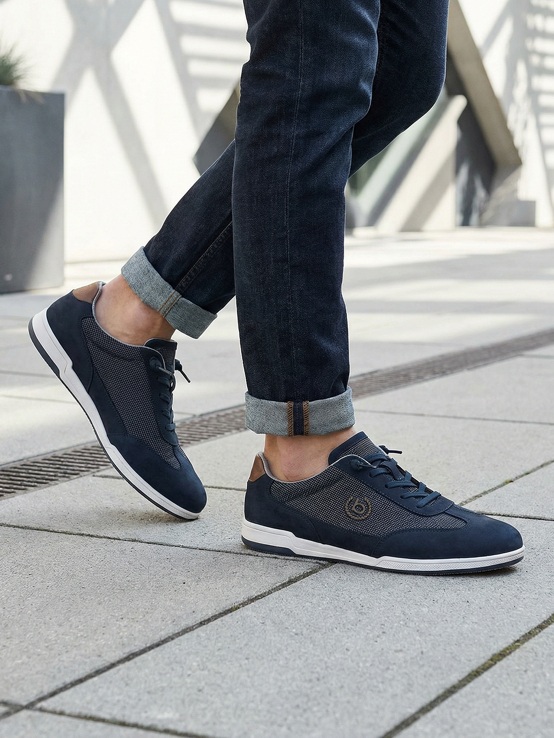 Lifestyle shot of bugatti SOLAR EXKO dark blue sneakers, featuring premium leather, suede and mesh upper, and white soles.
