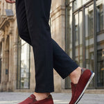 Lifestyle shot of bugatti Chesley dark red leather slip-on shoes, paired with dark dress pants.
