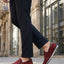 Lifestyle shot of bugatti Chesley dark red leather slip-on shoes, paired with dark dress pants.
