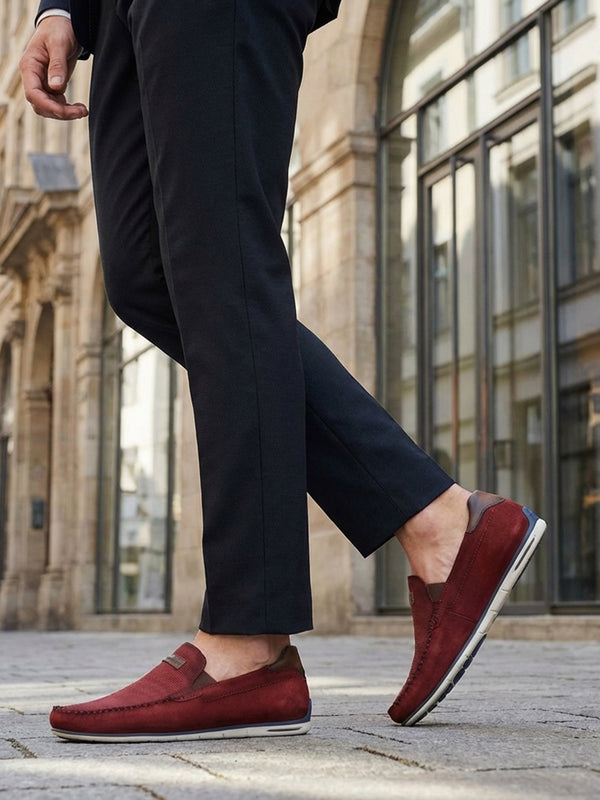 Lifestyle shot of bugatti Chesley dark red leather slip-on shoes, paired with dark dress pants.
