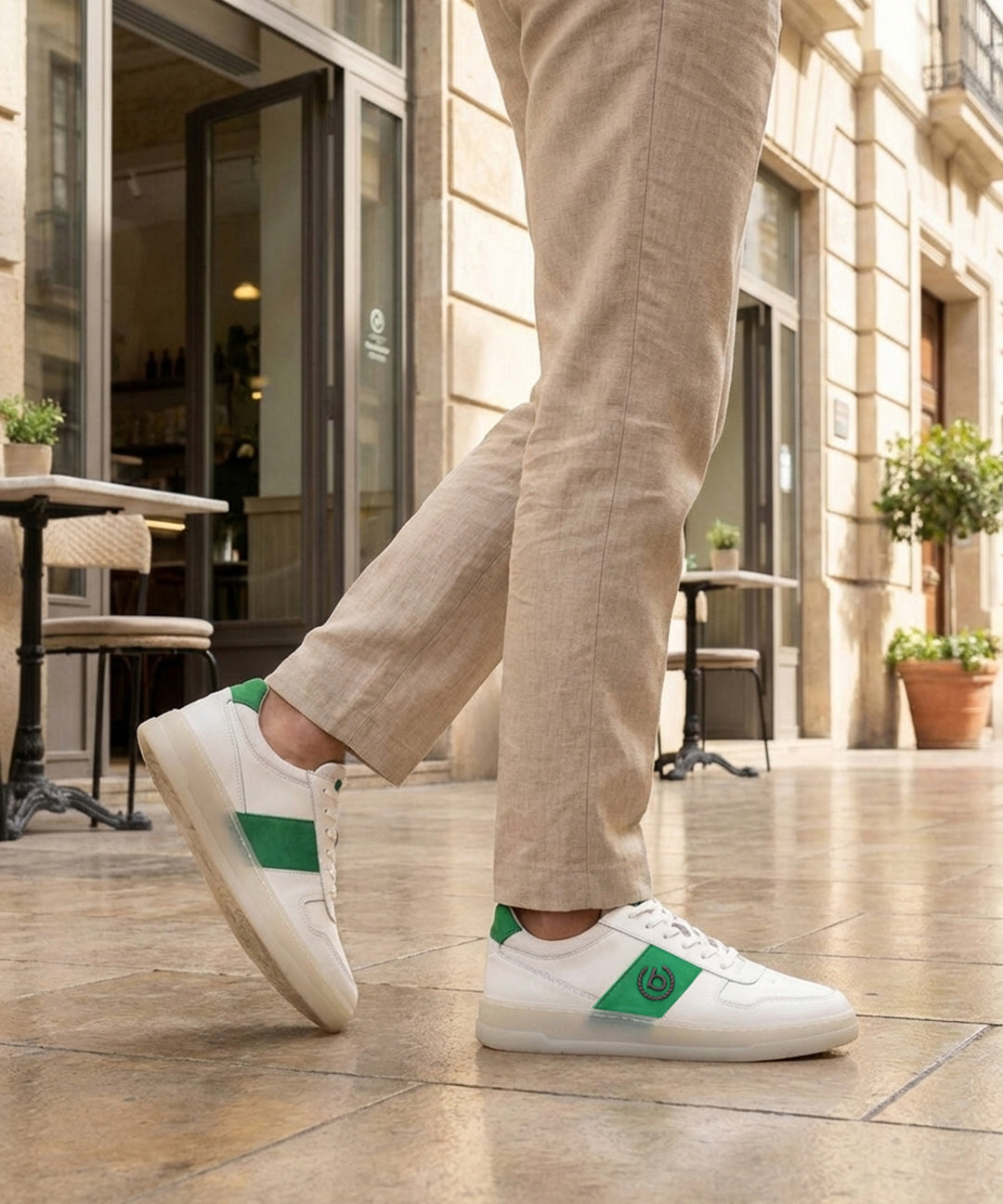 Lifestyle shot of bugatti Franc White premium leather sneakers, featuring a green stripe, worn with khaki trousers.