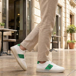Lifestyle shot of bugatti Franc White premium leather sneakers, featuring a green stripe, worn with khaki trousers.