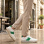 Lifestyle shot of bugatti Franc White premium leather sneakers, featuring a green stripe, worn with khaki trousers.