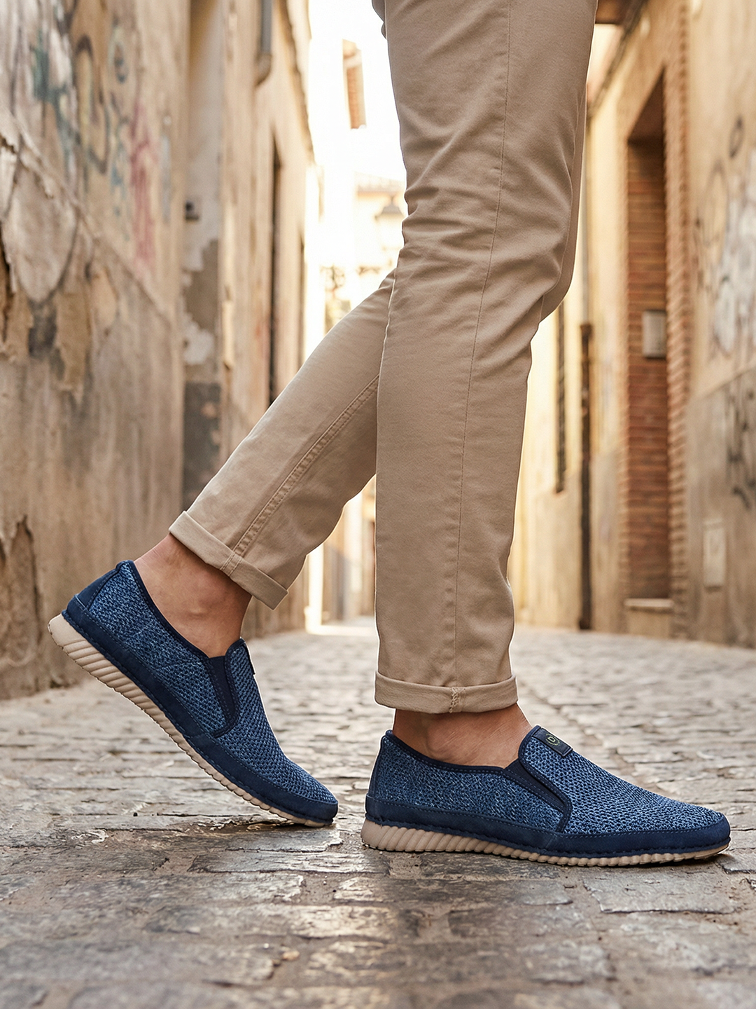 Lifestyle image of bugatti Colville blue casual slip-on shoe with a knit texture and beige sole.
