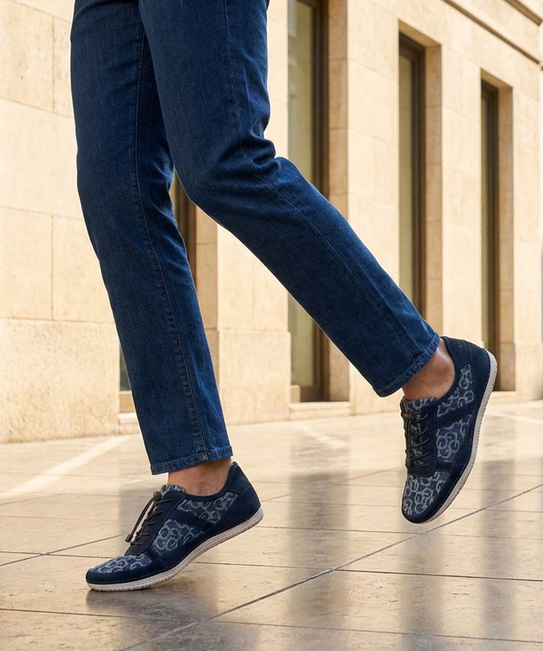 Lifestyle shot of bugatti Bimini light blue comfort sneakers with a floral pattern, paired with denim jeans.
