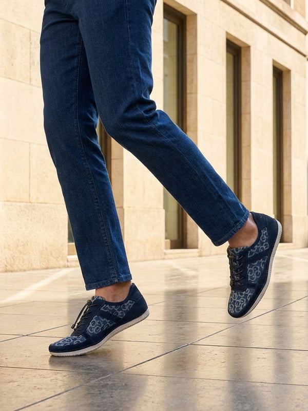Lifestyle shot of bugatti Bimini light blue comfort sneakers with a floral pattern, paired with denim jeans.
