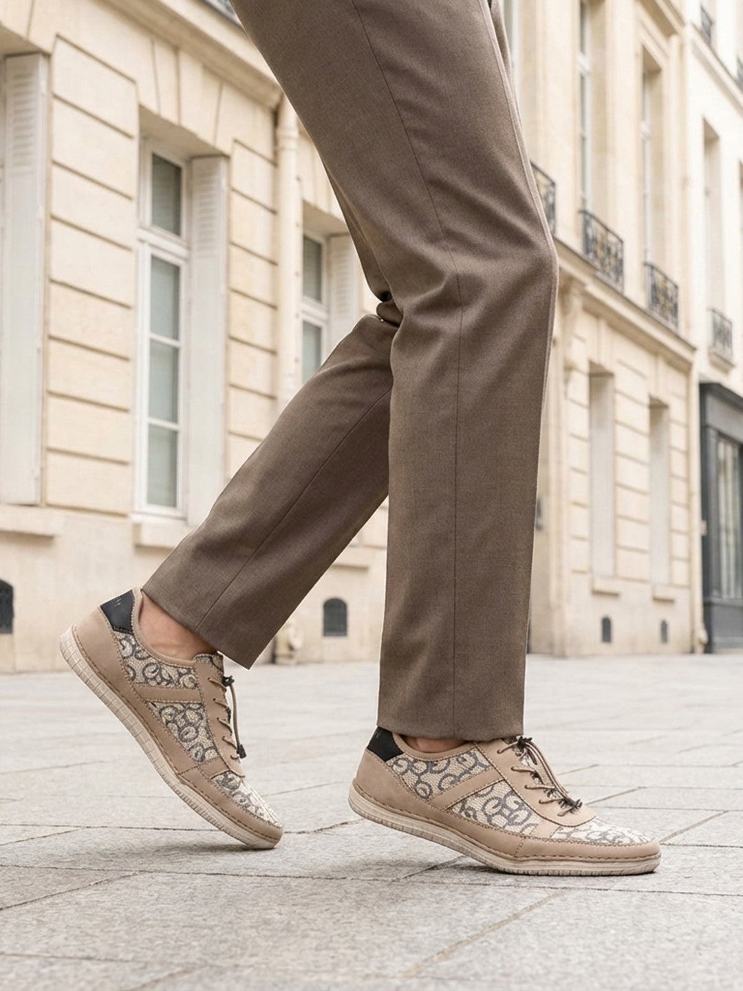 bugatti Bimini beige comfort sneakers with a lace-up closure, complemented by brown trousers, in a lifestyle shot.
