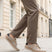 bugatti Bimini beige comfort sneakers with a lace-up closure, complemented by brown trousers, in a lifestyle shot.
