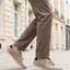 bugatti Bimini beige comfort sneakers with a lace-up closure, complemented by brown trousers, in a lifestyle shot.
