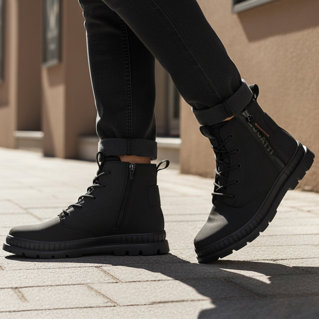 Lifestyle shot of bugatti Pallario comfort black casual boots, with zipper detail and lug sole, worn with dark rolled jeans.
