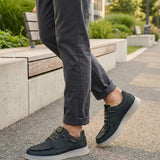 Lifestyle view of bugatti Fiero black comfort sneakers, worn with rolled dark gray pants, on a paved walkway.
