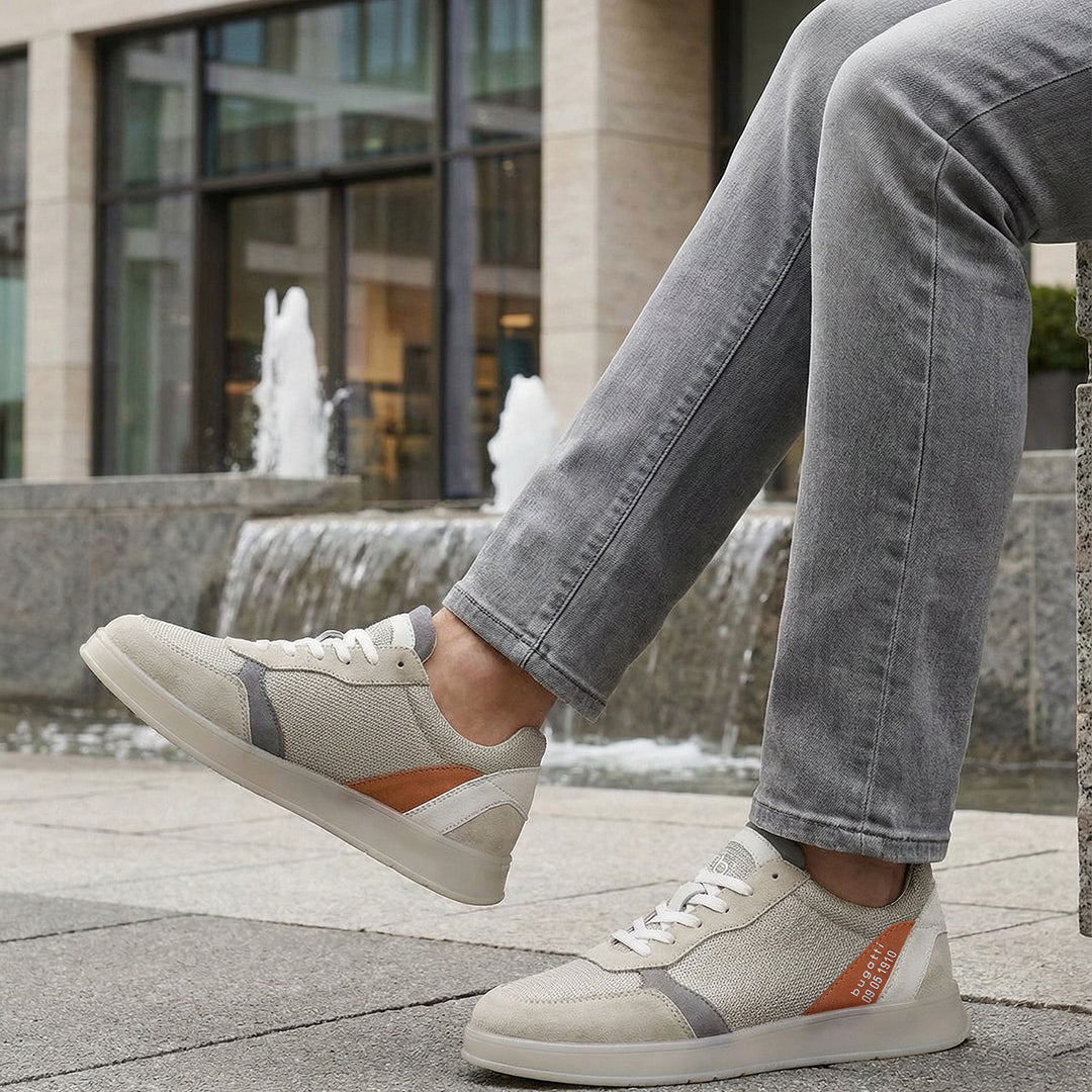 Lifestyle view of bugatti Fiero grey sneakers featuring a breathable textile upper with orange and gray accents.
