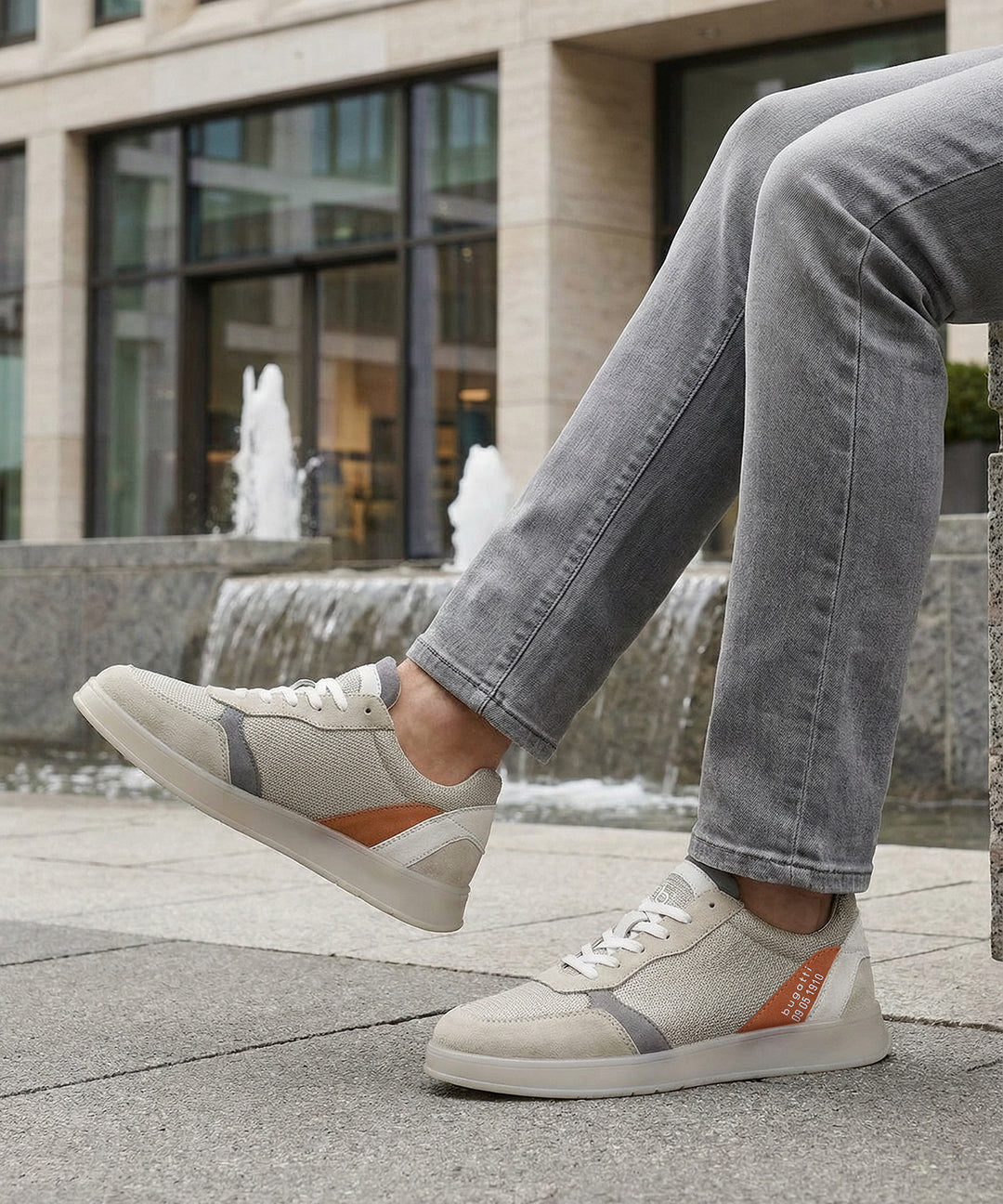 Lifestyle view of bugatti Fiero grey sneakers featuring a breathable textile upper with orange and gray accents.

