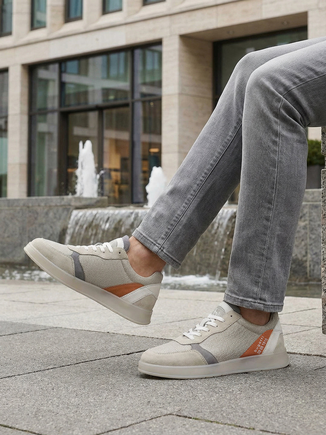 Lifestyle view of bugatti Fiero grey sneakers featuring a breathable textile upper with orange and gray accents.
