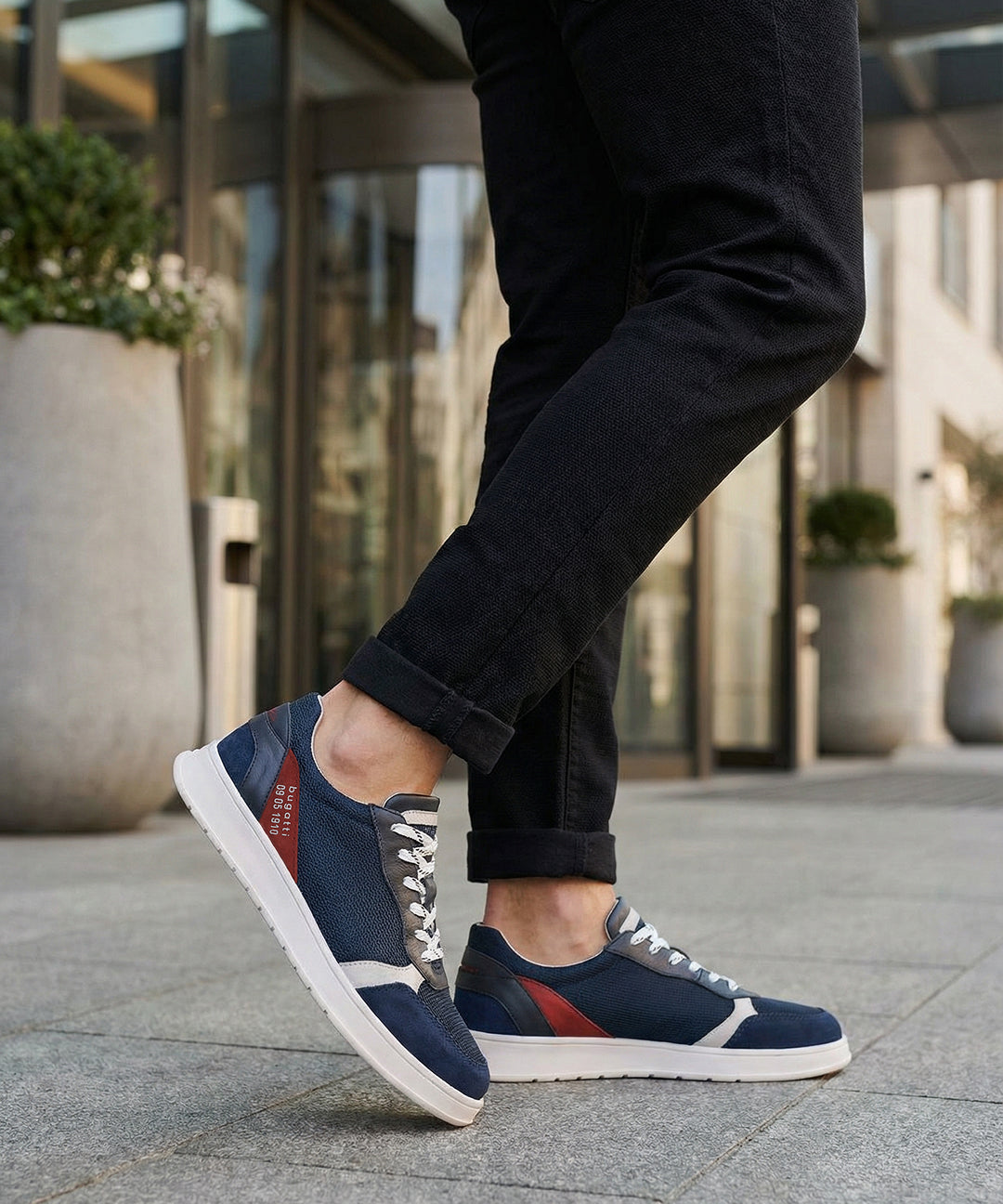 Lifestyle view of bugatti Fiero dark blue comfort sneakers, with white soles and grey laces, worn with dark jeans.
