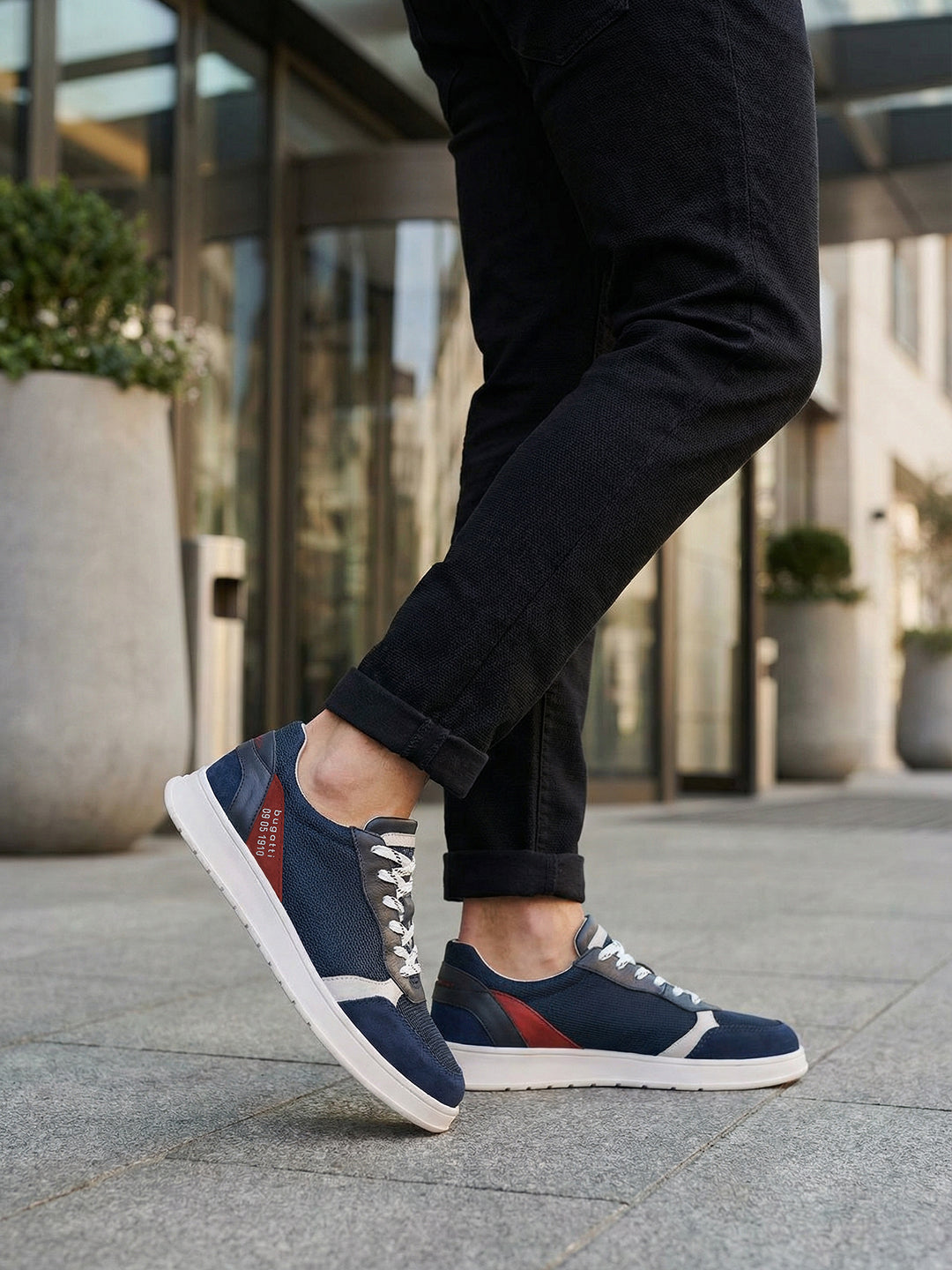 Lifestyle view of bugatti Fiero dark blue comfort sneakers, with white soles and grey laces, worn with dark jeans.
