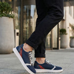 Lifestyle view of bugatti Fiero dark blue comfort sneakers, with white soles and grey laces, worn with dark jeans.
