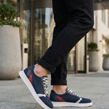 Lifestyle view of bugatti Fiero dark blue comfort sneakers, with white soles and grey laces, worn with dark jeans.
