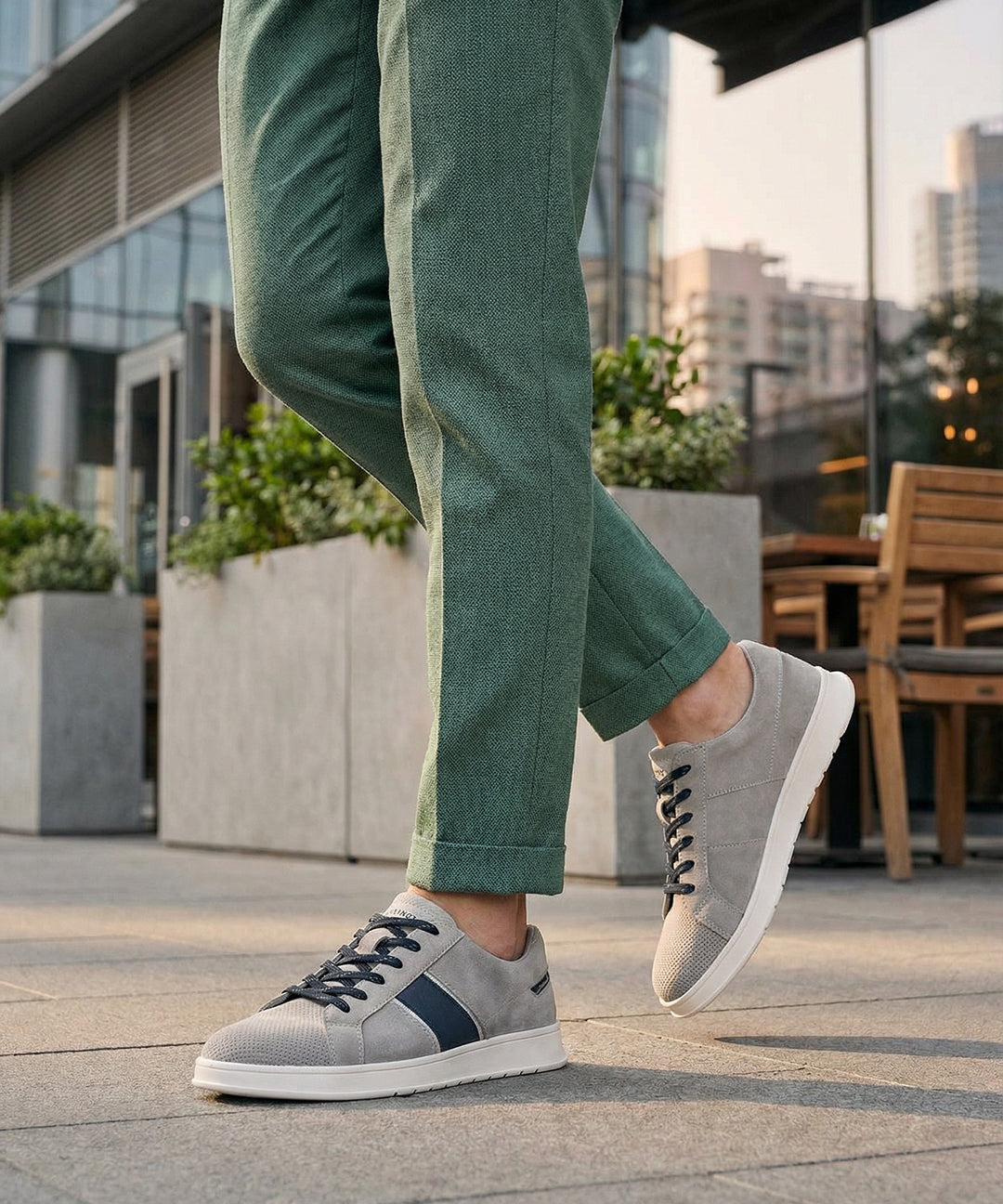 Lifestyle image of bugatti Fiero grey leather sneakers, with dark laces and a navy stripe detail.
