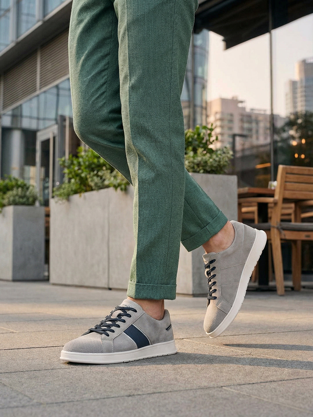 Lifestyle image of bugatti Fiero grey leather sneakers, with dark laces and a navy stripe detail.
