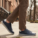 Lifestyle view of bugatti Fiero dark blue leather sneakers with a light grey sole and heel.