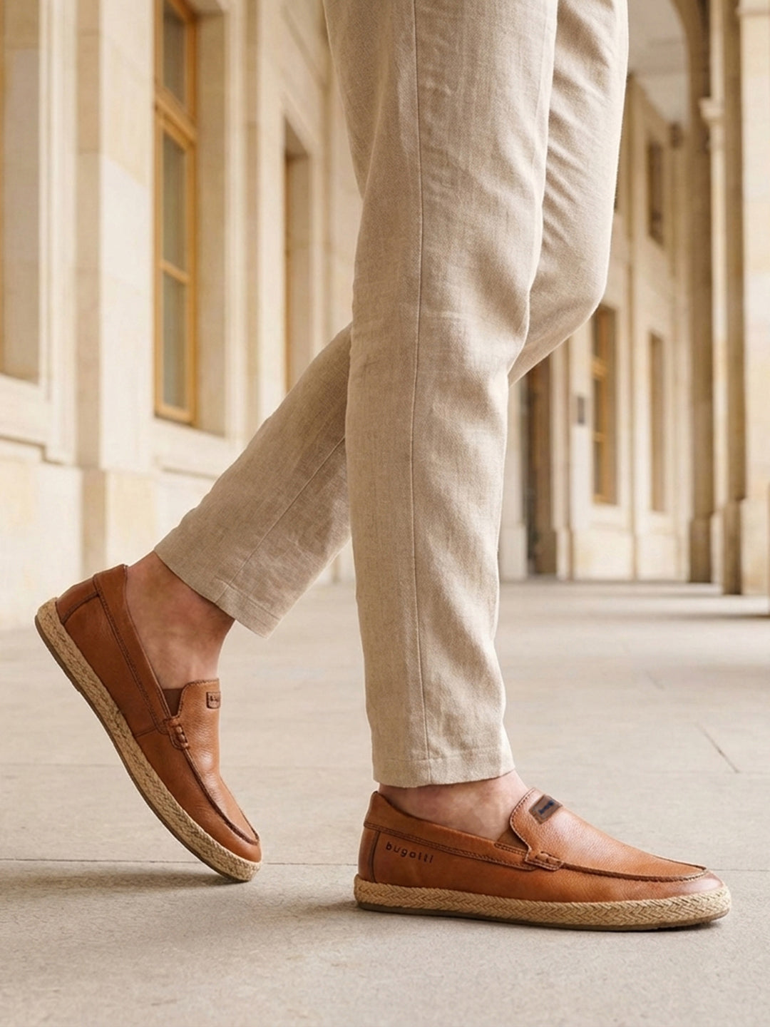 Lifestyle shot of a man wearing bugatti Spendril Cognac leather slip-on shoes with light brown linen pants.