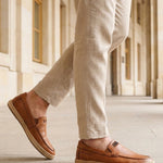 Lifestyle shot of a man wearing bugatti Spendril Cognac leather slip-on shoes with light brown linen pants.