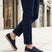 Lifestyle image of bugatti Spendril dark blue leather slip-on shoes with a jute sole, worn with cuffed navy pants.
