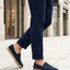 Lifestyle image of bugatti Spendril dark blue leather slip-on shoes with a jute sole, worn with cuffed navy pants.
