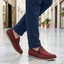 Lifestyle shot of bugatti Clipperton red leather slip-on casual shoes with blue pants, worn on marble floor.