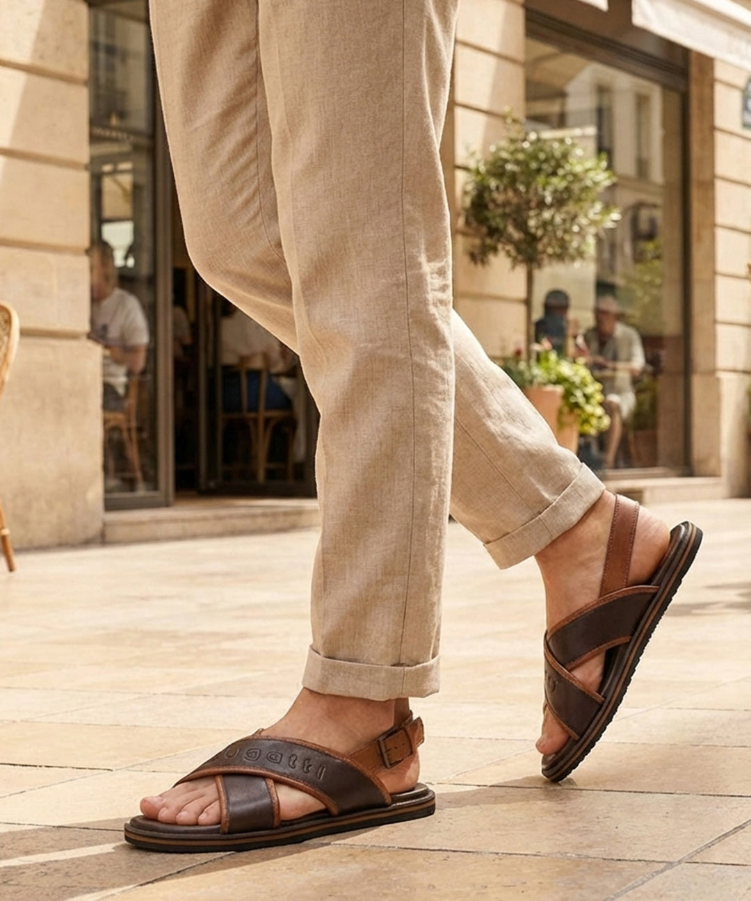 Lifestyle view of bugatti Cobie dark brown leather sandals with adjustable back strap, paired with beige linen pants.