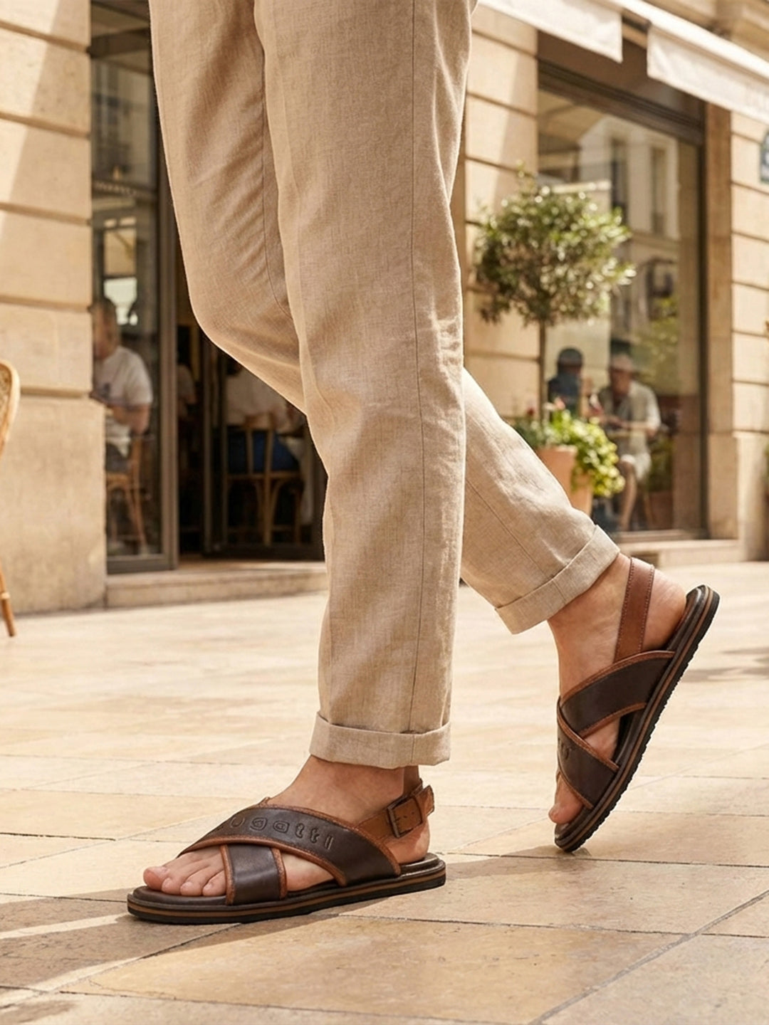 Lifestyle view of bugatti Cobie dark brown leather sandals with adjustable back strap, paired with beige linen pants.