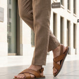 Lifestyle view of bugatti cognac leather sandals with adjustable back strap worn with tan pants.
