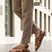 Lifestyle view of bugatti cognac leather sandals with adjustable back strap worn with tan pants.
