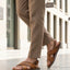 Lifestyle view of bugatti cognac leather sandals with adjustable back strap worn with tan pants.
