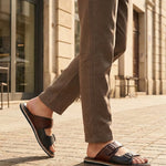 bugatti Cobie dark blue leather sandals with two straps, worn with brown trousers.