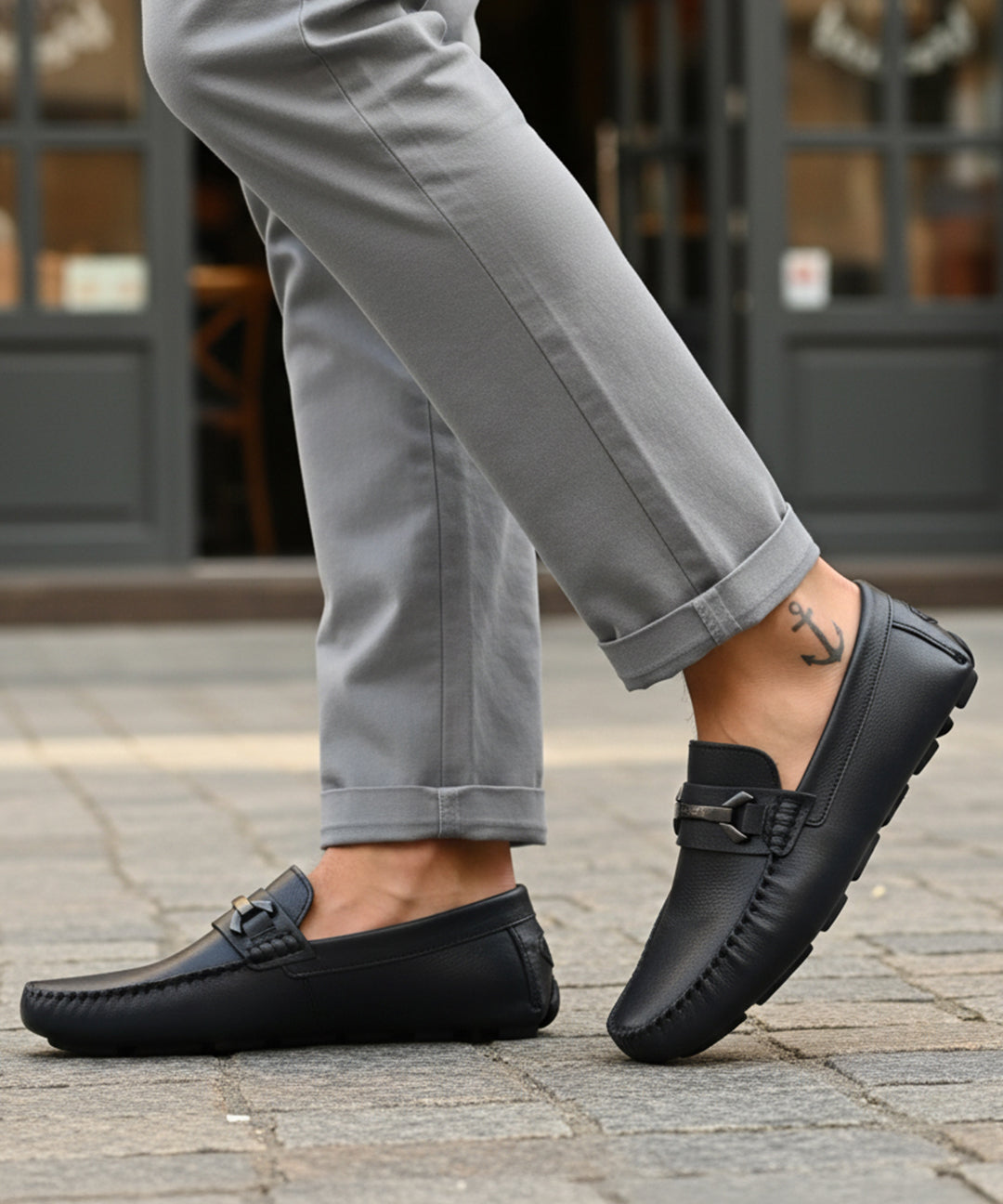 Lifestyle shot of bugatti Olexa dark blue leather slip-ons with a metal accent, worn with gray pants.