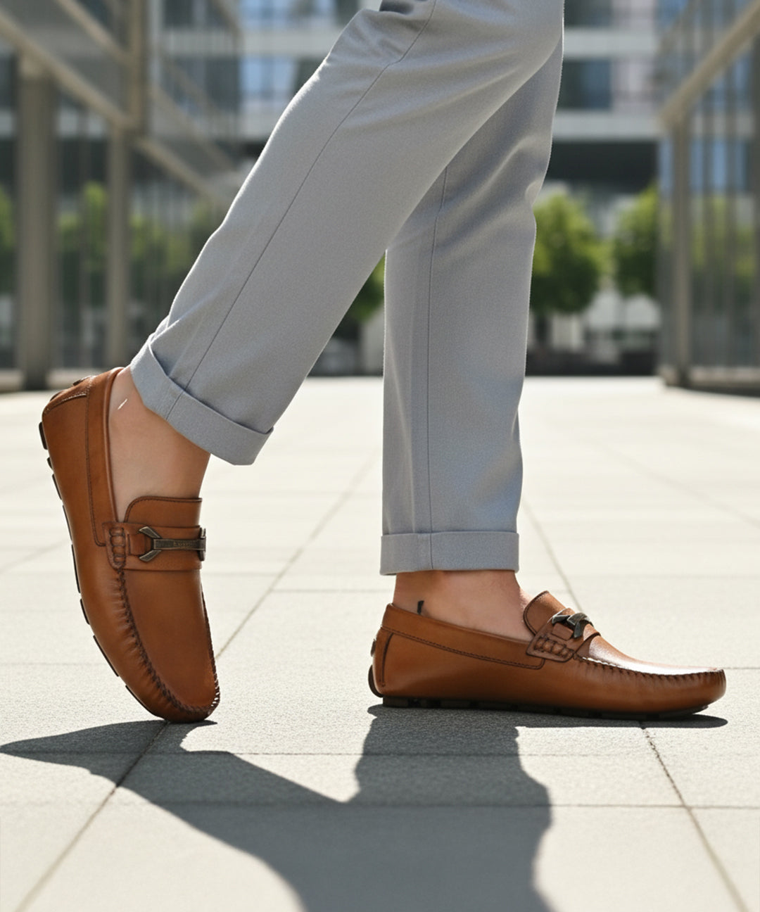 Lifestyle image of bugatti Olexa cognac leather slip-on shoes with rolled grey trousers.
