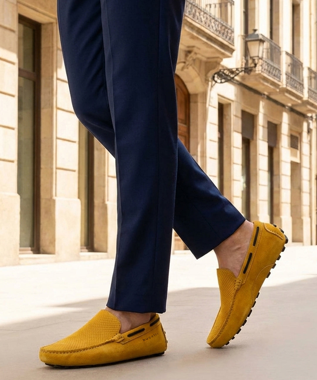 Lifestyle cropped image of bugatti Manfield yellow leather slip-on shoes with dark blue slacks.
