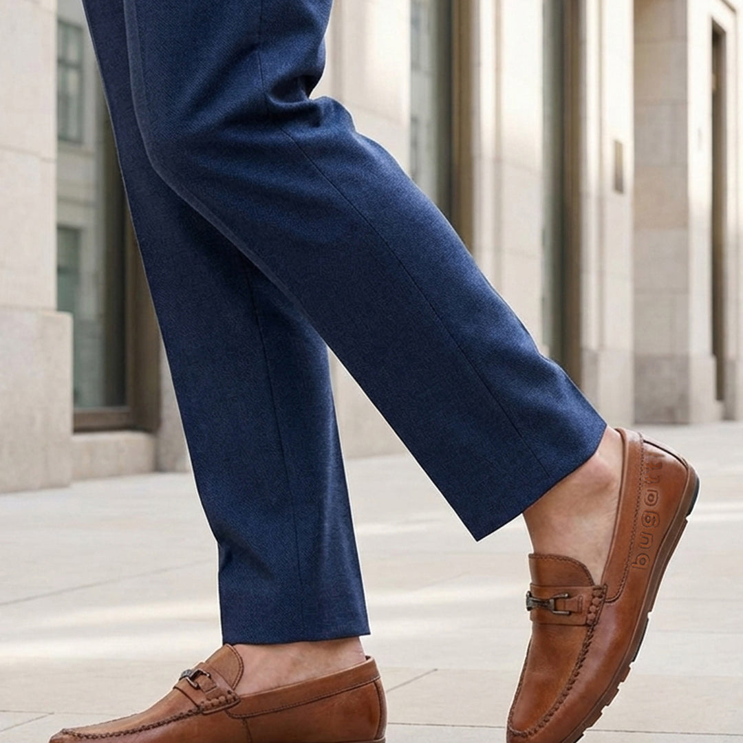 Lifestyle shot of a man wearing bugatti Cobe Cognac leather slip-on shoes with blue dress pants.
