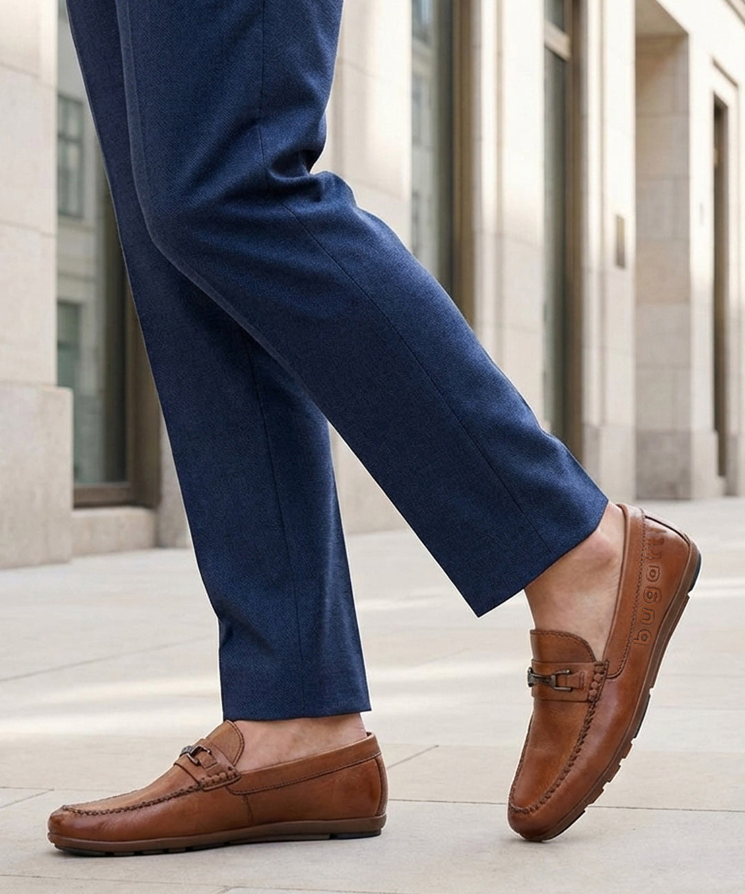 Lifestyle shot of a man wearing bugatti Cobe Cognac leather slip-on shoes with blue dress pants.