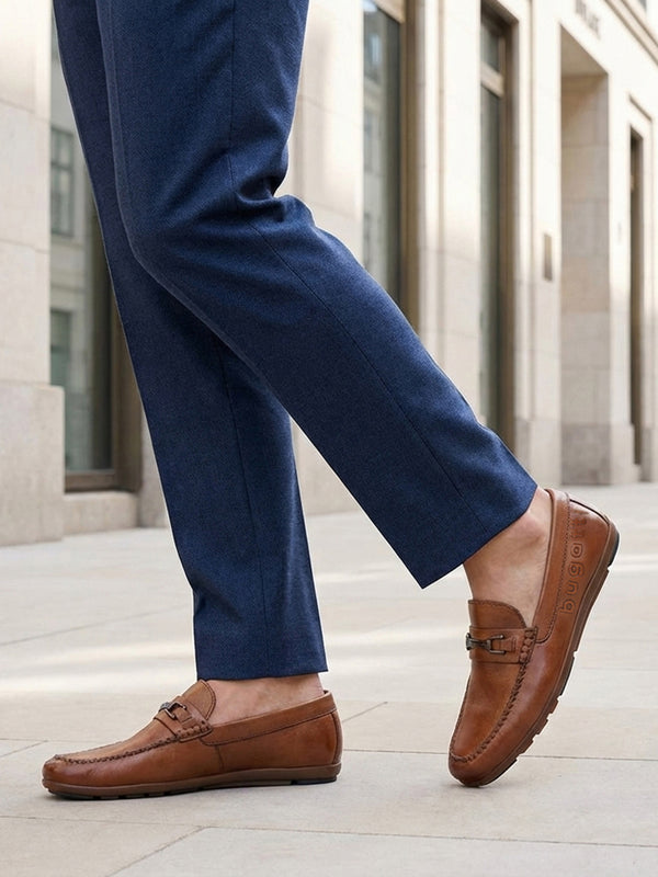 Lifestyle shot of a man wearing bugatti Cobe Cognac leather slip-on shoes with blue dress pants.