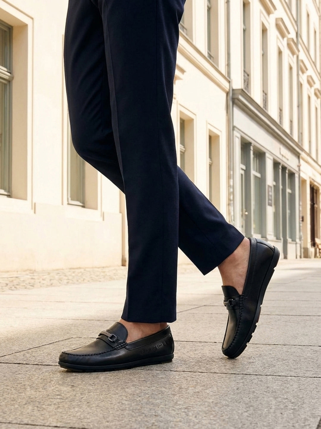 Lifestyle shot of bugatti Cobe Black premium leather slip-on shoes, paired with dark-colored pants.