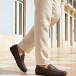 Lifestyle cropped view of a man walking in bugatti dark brown leather slip-on shoes with a basket weave texture.
