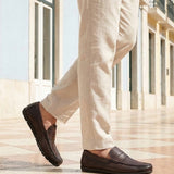Lifestyle cropped view of a man walking in bugatti dark brown leather slip-on shoes with a basket weave texture.
