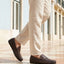 Lifestyle cropped view of a man walking in bugatti dark brown leather slip-on shoes with a basket weave texture.

