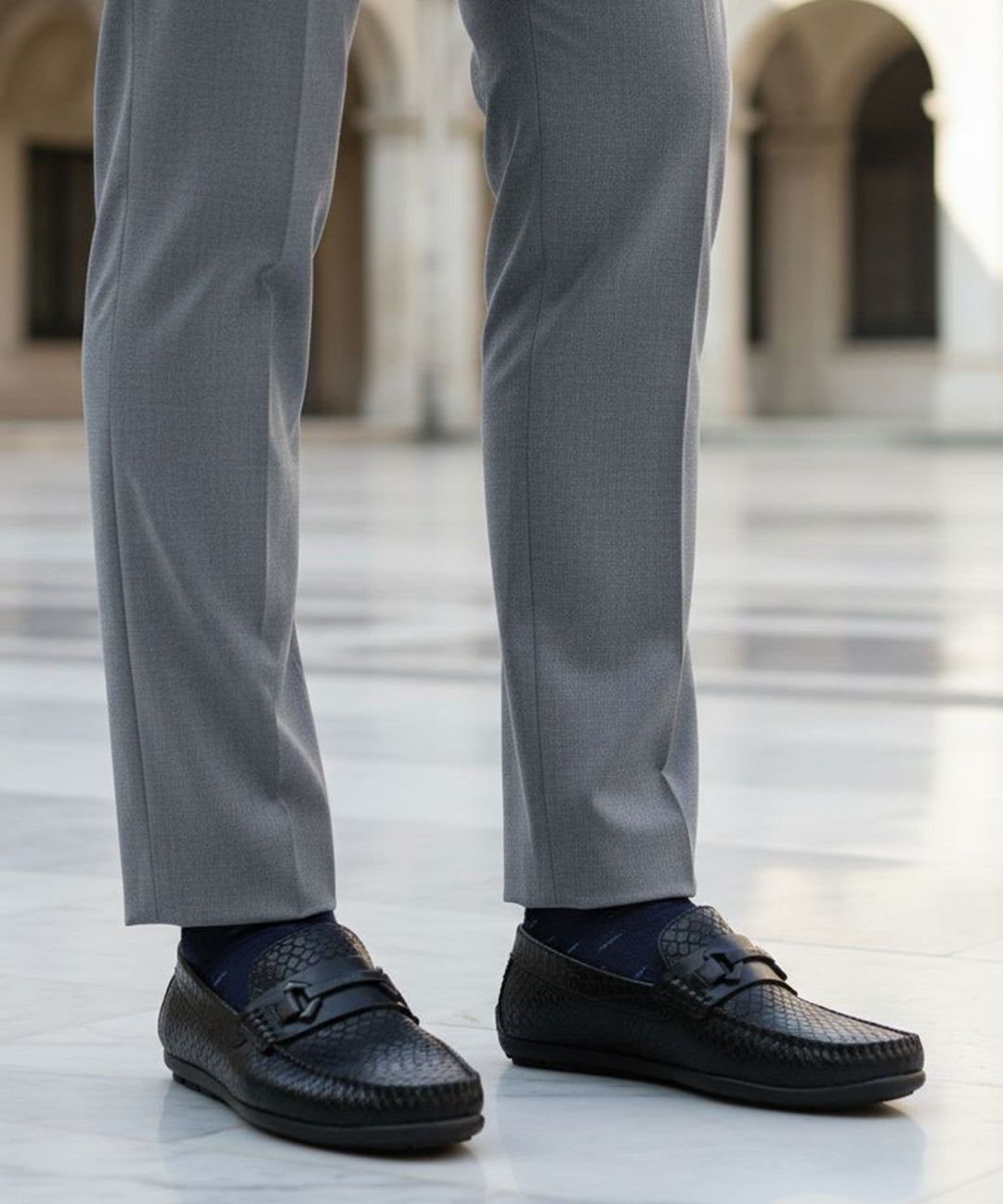 bugatti Linex black casual slip-ons in premium leather, worn with gray dress pants and dark socks.

