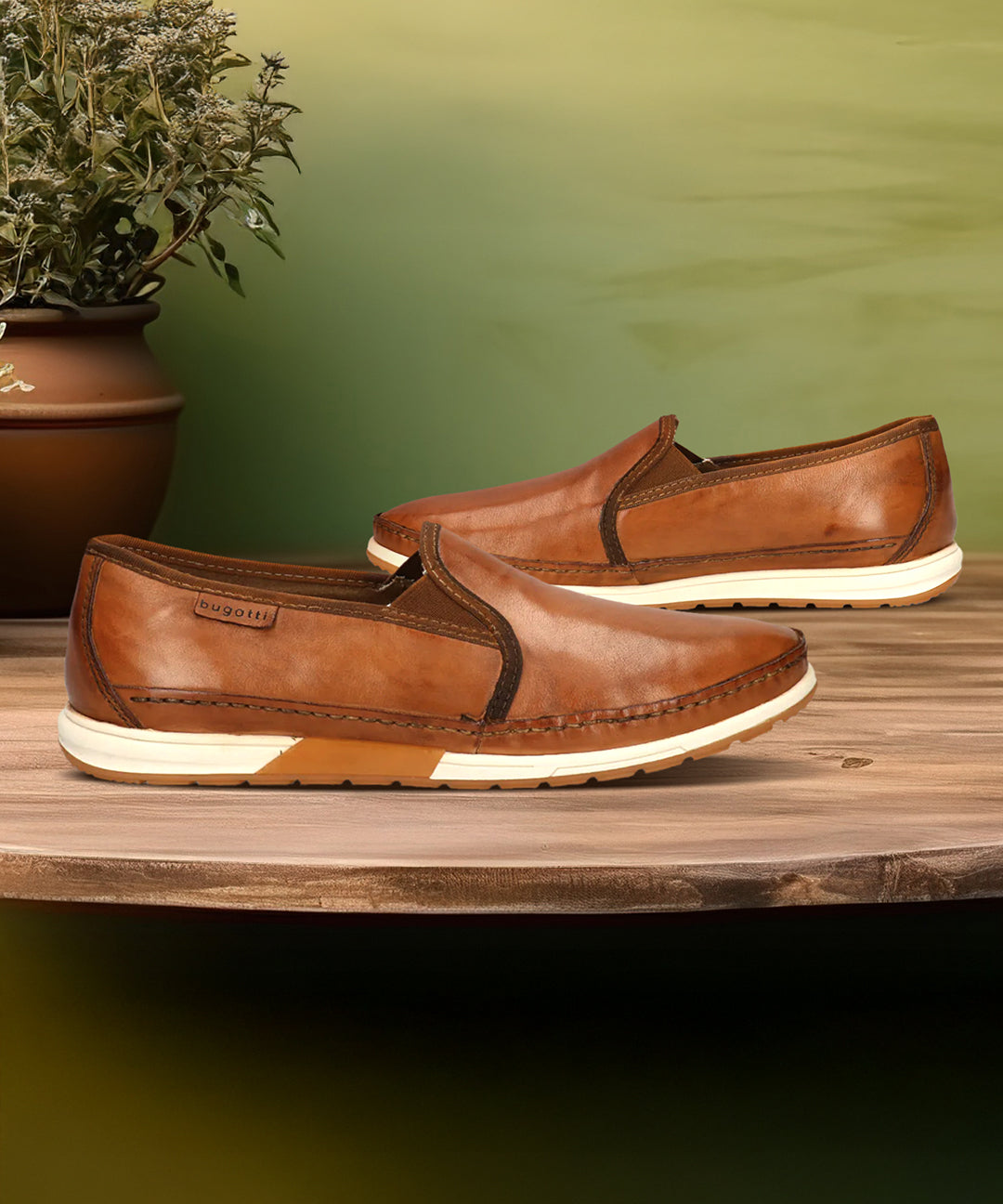 bugatti Stowe light brown leather slip-on sneakers with white soles on a wooden surface.