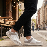 Lifestyle shot of bugatti Franc White sneakers in white leather and grey suede, worn with black jeans.